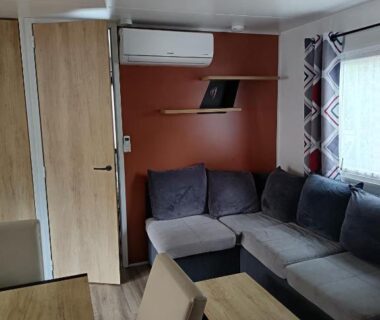 Salon avec canapé et table à manger dans le mobil-home MH F101 Camping Bois Masson