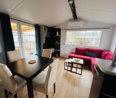 Séjour avec canapé rouge et coin repas dans le MH J08 du Camping Siblu La Plage