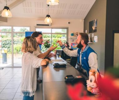 Réception intérieure avec clients et réceptionniste au Camping Siblu La plage