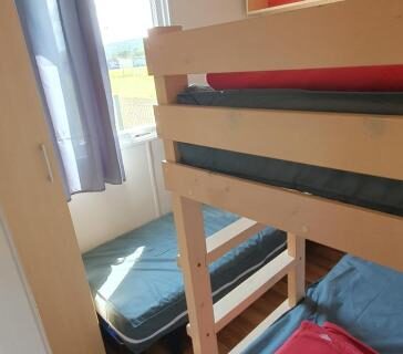 Chambre avec lits superposés et porte fenêtre vers l'extérieur du MH135 camping NOVELA Mobil home 5pl climatisé