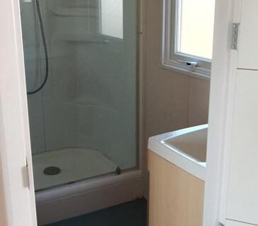 Salle d'eau avec douche vitrée et lavabo dans le mobil home MH135 camping NOVELA