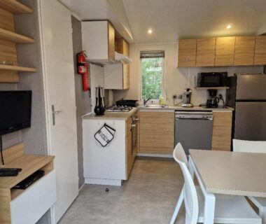 Intérieur avec cuisine équipée réfrigérateur télévision et coin repas du mobil-home MH3-Confort Plus