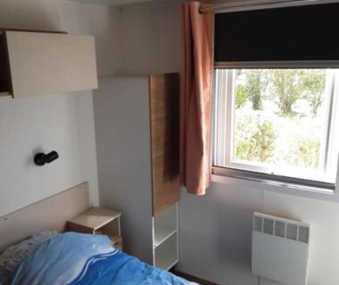 Chambre avec lit, armoire et fenêtre dans le mobil home du Domaine de Kerlann