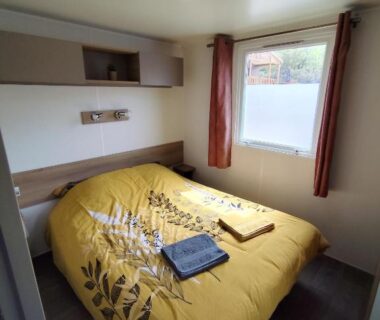 Chambre avec lit double couette jaune et fenêtre du MOBIL HOME 40M2 ECRIN DE VERDURE