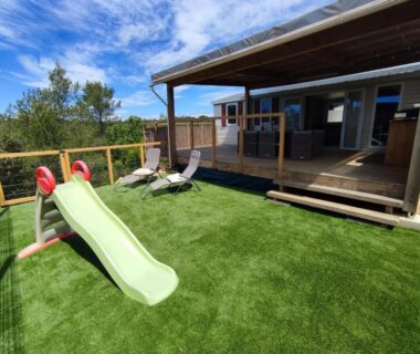 Terrasse avec pelouse synthétique, toboggan et transats du MOBIL HOME 40M2 ECRIN DE VERDURE