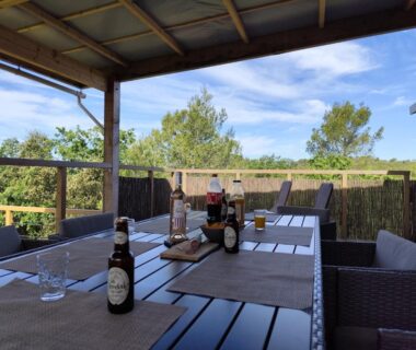Terrasse couverte avec table à manger, boissons et transats du MOBIL HOME 40M2 ECRIN DE VERDURE