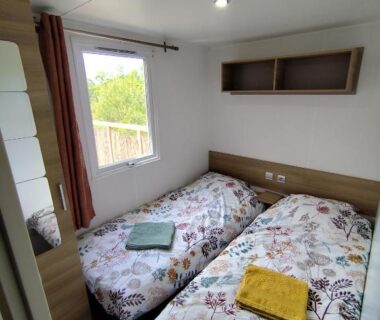Chambre avec deux lits jumeaux et fenêtre donnant sur verdure dans le MOBIL HOME 40M2 ECRIN DE VERDURE