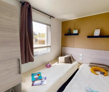 Chambre avec deux lits simples et fenêtre dans le Mobil Home 4p