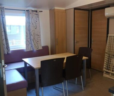Intérieur coin repas avec table banquette et chaises dans le mobil home 6 places climatisé