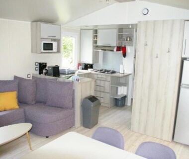 Intérieur avec canapé coin repas et cuisine équipée du mobil home 6/8 places