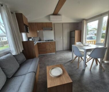 Coin séjour avec canapé, cuisine et table à manger dans le mobil home Biscarosse Lac