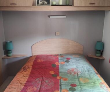 Intérieur chambre avec lit double lampes et rangements dans le mobil home MOBIL HOME CAMPING 3***