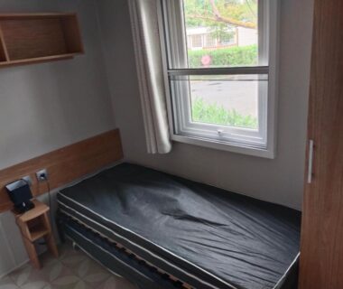 Chambre simple avec lit et fenêtre dans le mobil home Le Lozérien