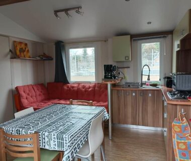 Intérieur salon avec kitchenette table et canapé du MOBIL HOME LMNP GUIGON