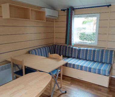 Séjour avec banquette rayée et table dans le mobil home Lucky climatisé du camping Port la Nouvelle