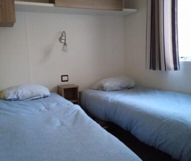 Chambre avec deux lits simples et une table de chevet dans le mobil home Domaine de Kerlann