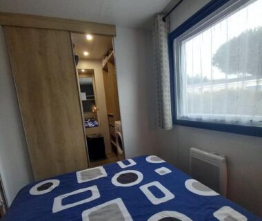 Intérieur chambre avec lit et fenêtre dans le mobil home Tout Confort du Camping LA RESERVE