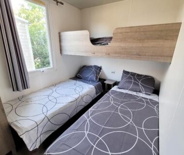 Chambre avec trois lits et petite fenêtre dans le mobil-home d'Anne et Edouard