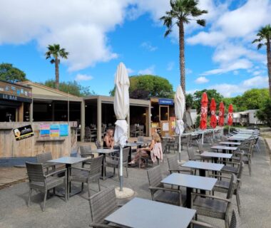 Terrasse extérieure avec tables parasols et palmiers au MOBIL-HOME d’Anne et Edouard