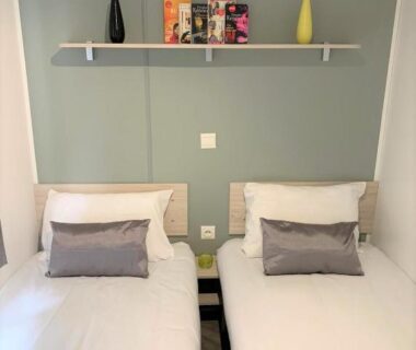 Chambre avec deux lits et étagère décorative dans le MOBILHOME 3 CH CAMPING 4*