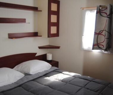Chambre avec lit double et fenêtre dans le MOBILHOME 3 CHAMBRES