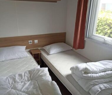 Chambre avec deux lits simples et fenêtre dans le mobilhome 3 CHBRES 2 SDE 2 WC