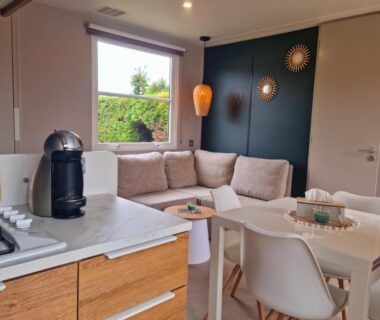 Salon avec canapé et coin cuisine dans le MOBILHOME 6p 3 CH 2 SDB SAINT JEAN DE MONTS