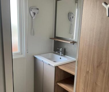 Salle de bain avec lavabo et sèche-cheveux dans MOBILHOME CAMPING 4 étoiles NARBONNE-PLAGE