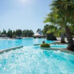 Piscine extérieure avec bain à remous et palmiers au Mobilhome Fabuleux Camping Vias Plage
