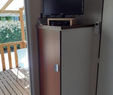 Intérieur avec meuble TV et terrasse visible dans le mobilhome agréable sans draps ni serviettes