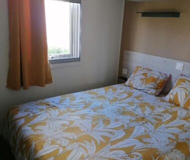 Chambre avec lit double et fenêtre dans le mobil home Le Narbonnais