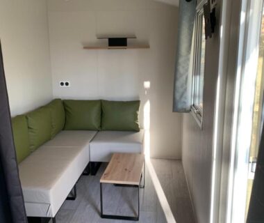 Salon intérieur avec canapé en L et table dans le mobil-home MODULO VIP
