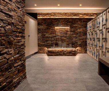 Vestiaire avec casiers banc et murs en pierre dans le spa du M&V Resort Camping