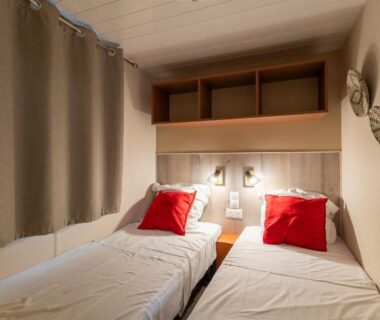 Chambre avec deux lits simples et coussins rouges au Maïana Resort