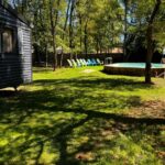 Jardin herbeux avec piscine hors sol et transats au Manoir le Mingreaud Bungalows