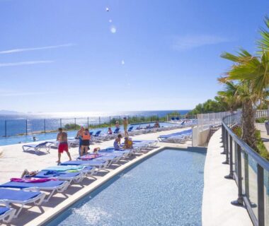 Bord de piscine avec transats et vue mer au Camping de l'Arquet