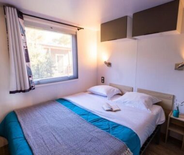 Chambre double avec lit et fenêtre dans le mobil-home du Camping de l'Arquet