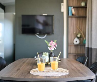 Coin repas intérieur avec table verres de jus et vase dans le mobil home Lou Cigalon
