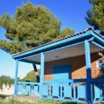 Terrasse en bois d'un chalet bleu dans la pinède aux Chalets de la Mer