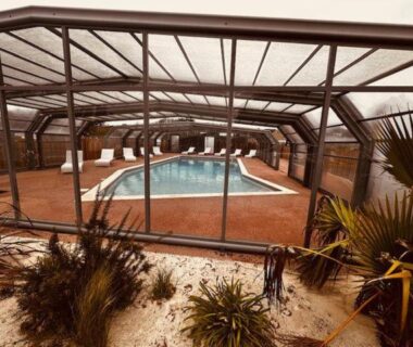 Piscine couverte avec chaises longues dans une véranda au camping Martinette