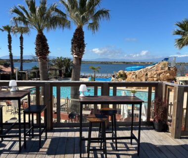 Terrasse avec tables palmiers et piscine au Mobil Home Menthalo 4 étoiles La Presqu île du Barcarés
