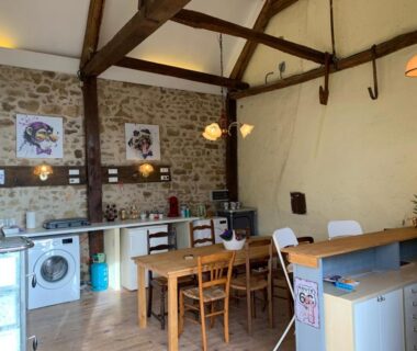 Cuisine commune avec table électroménager et poutres au Minicamping Sous les Cloches