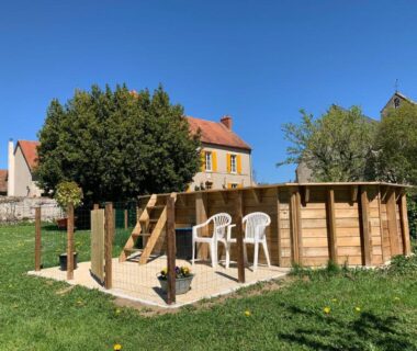 Jardin avec piscine hors sol en bois et deux chaises blanches au Minicamping Sous les Cloches