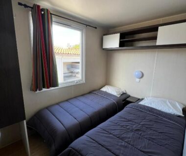 Chambre avec deux lits près de la fenêtre dans le Mobil Home 014 climatisé