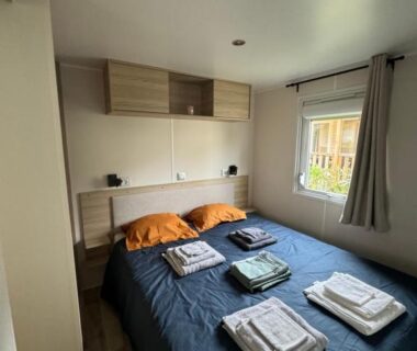 Chambre avec lit double rangements et serviettes dans le Mobil-Home