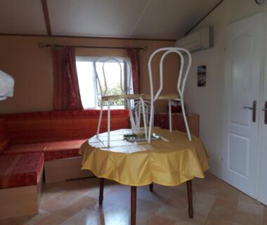Coin séjour avec table et chaises posées à l'envers dans le Mobil Home 14