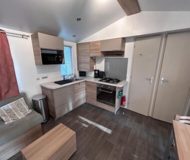 Intérieur avec kitchenette canapé et table dans le mobil home 2 chambres du Camping La Carabasse