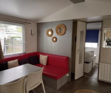 Séjour avec banquette rouge et coin repas dans le Mobil Home 2 chambres avec terrasse