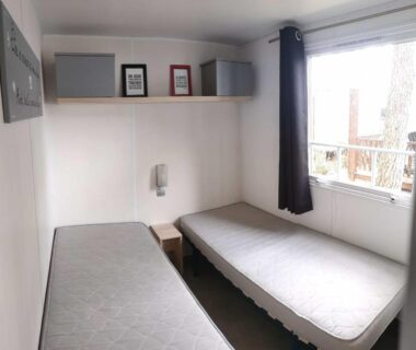Chambre intérieure avec deux lits et fenêtre du Mobil Home 2 chambres avec terrasse
