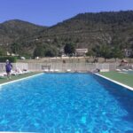 Piscine extérieure au camping avec transats et montagnes en arrière-plan au Mobil-Home